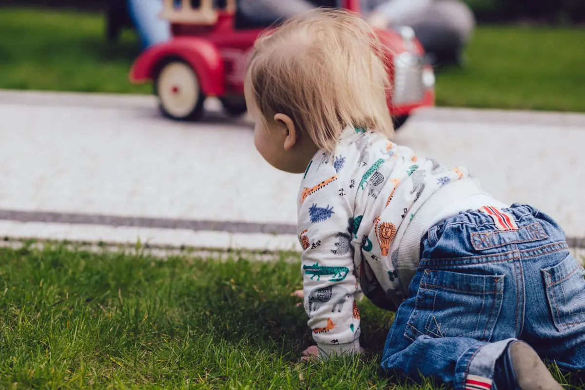 Desenvolvimento motor do bebê: criança engatinhando na grama