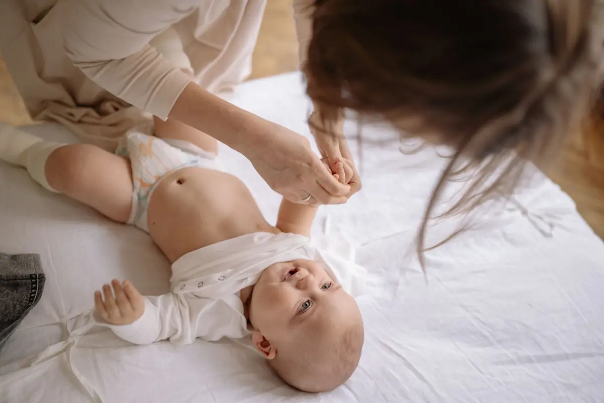 Lavagem nasal no bebê: mãe cuidando do bebê deitado no trocador